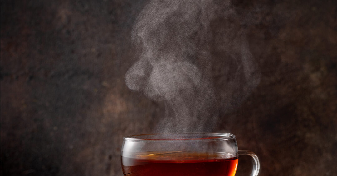 Cup of hot tea with a steam on dark background