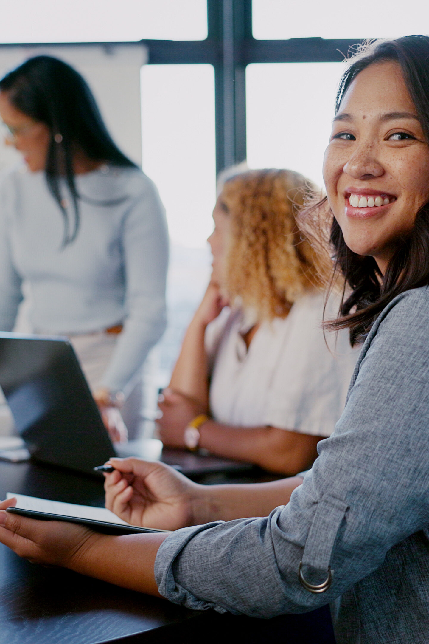 Business meeting, portrait and woman writing with team for planning, strategy and marketing idea in office. Design, collaboration and face of designer with notes for group project, vision and mission