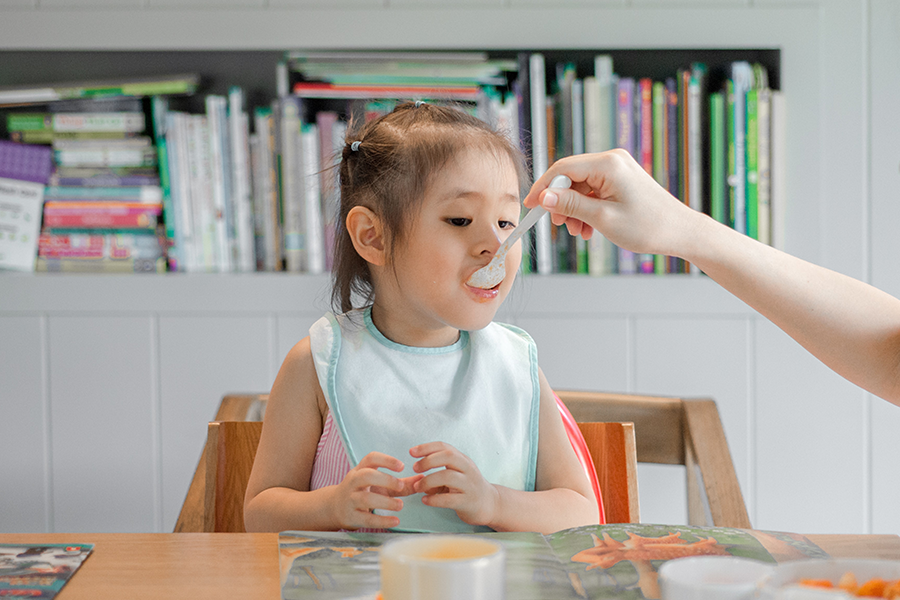child being fed in a high chair