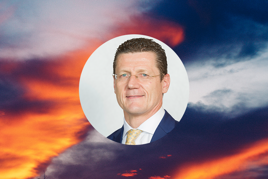 Etienne Sanz de Acedo headshot over an orange and blue sunset