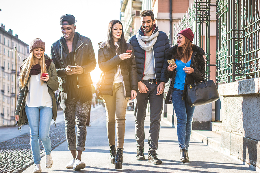 Gen-Z-walking-down-city-street-mobile-phones-smiling