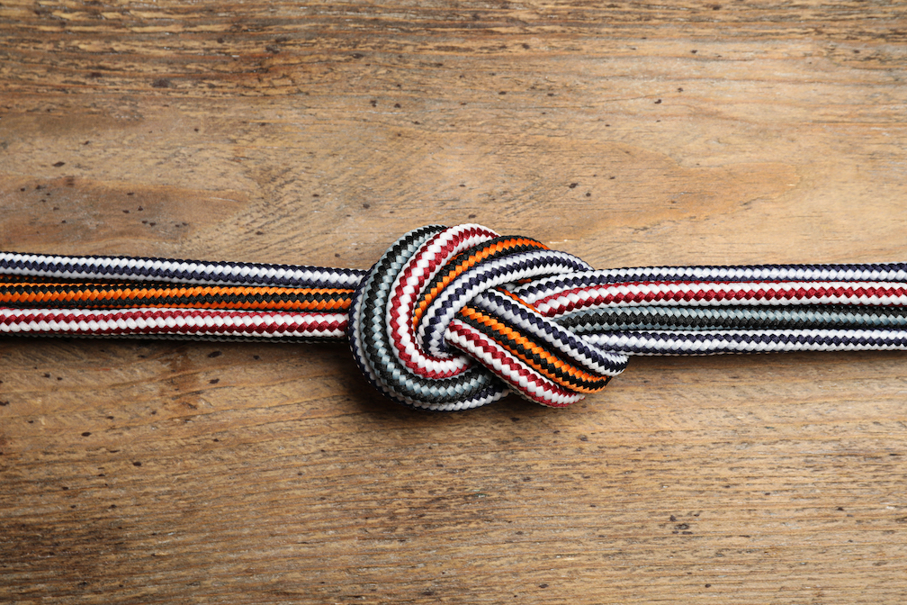 Colorful Ropes Tied Together On Wooden Background, Top View. Unity Concept